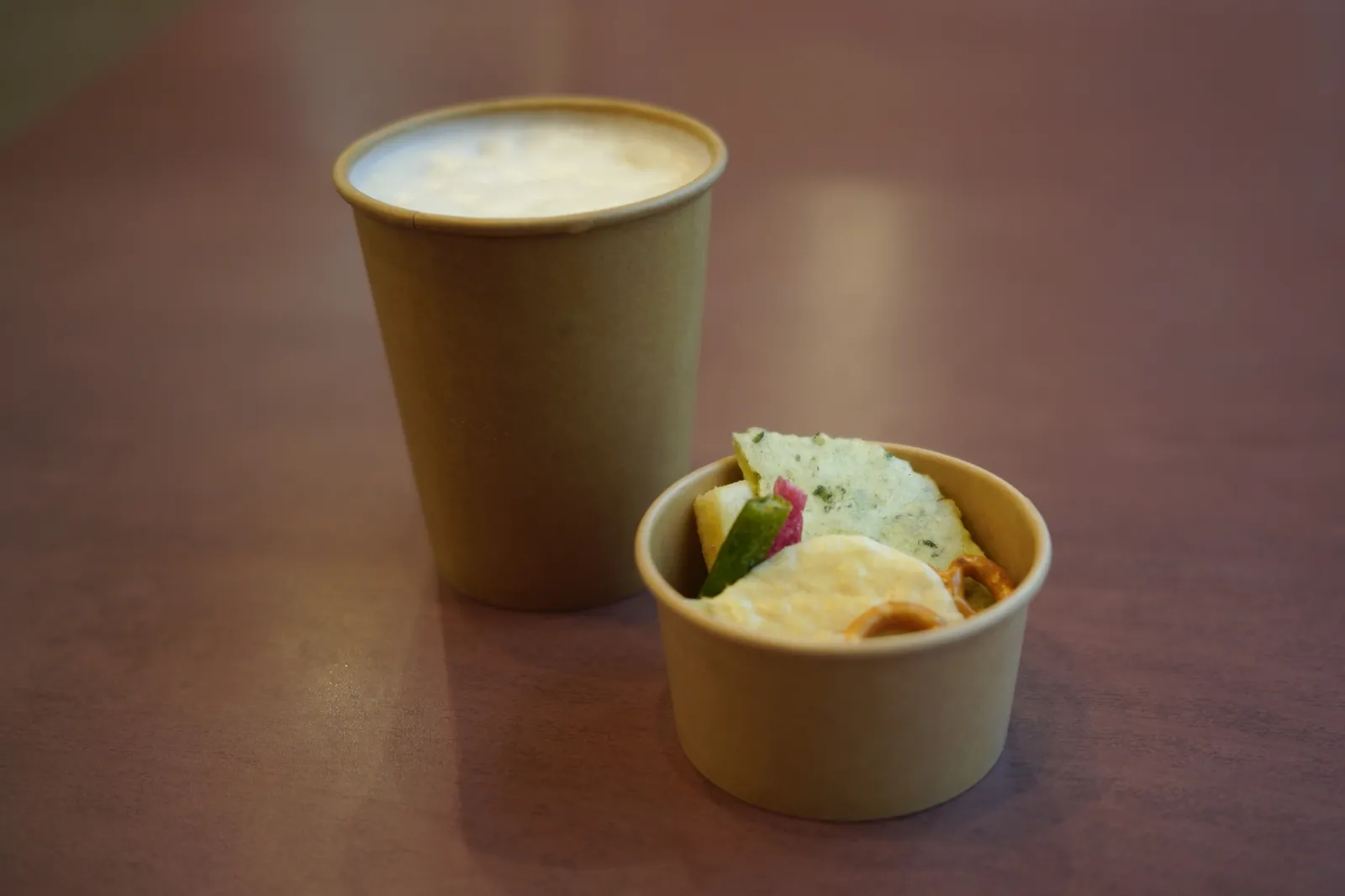 紙コップに注いだビールと、おせんべい・野菜チップスの入った紙カップ