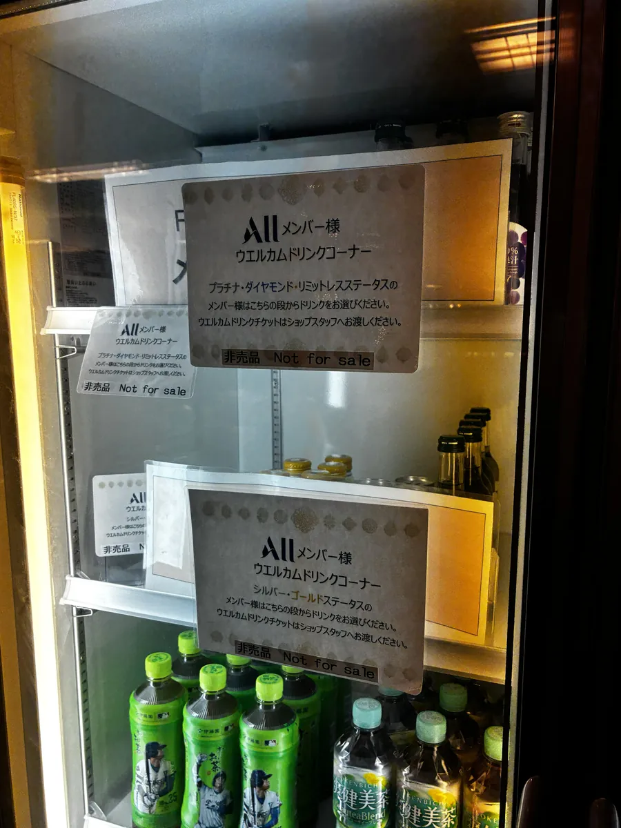 ショップの冷蔵庫。ALLメンバー向けウエルカムドリンクコーナーの案内が貼られ、ステータス別に棚が分かれている